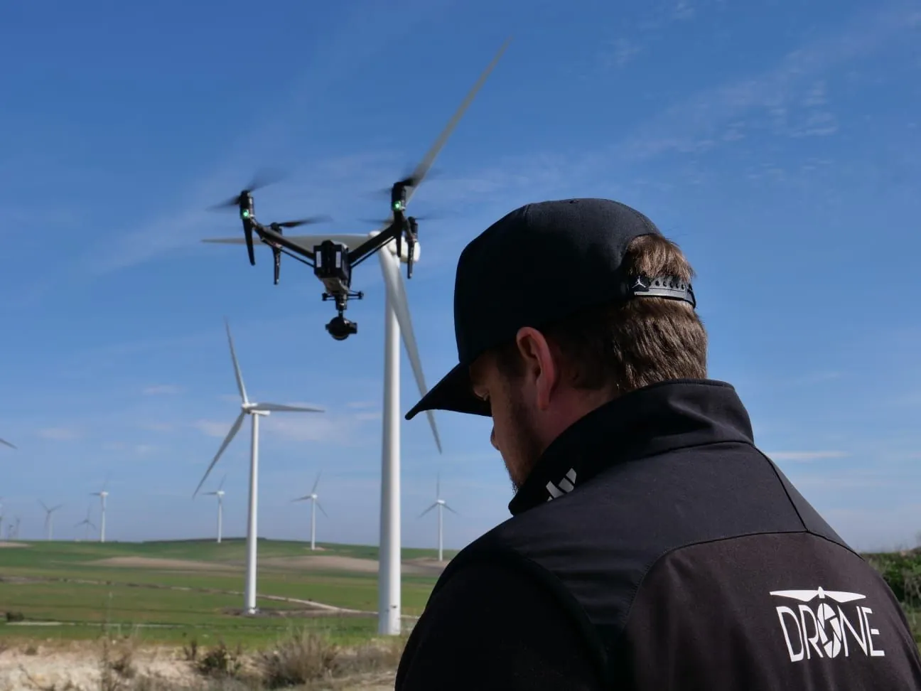Piloto de DroneJaén operando un DJI Inspire junto a un parque eólico